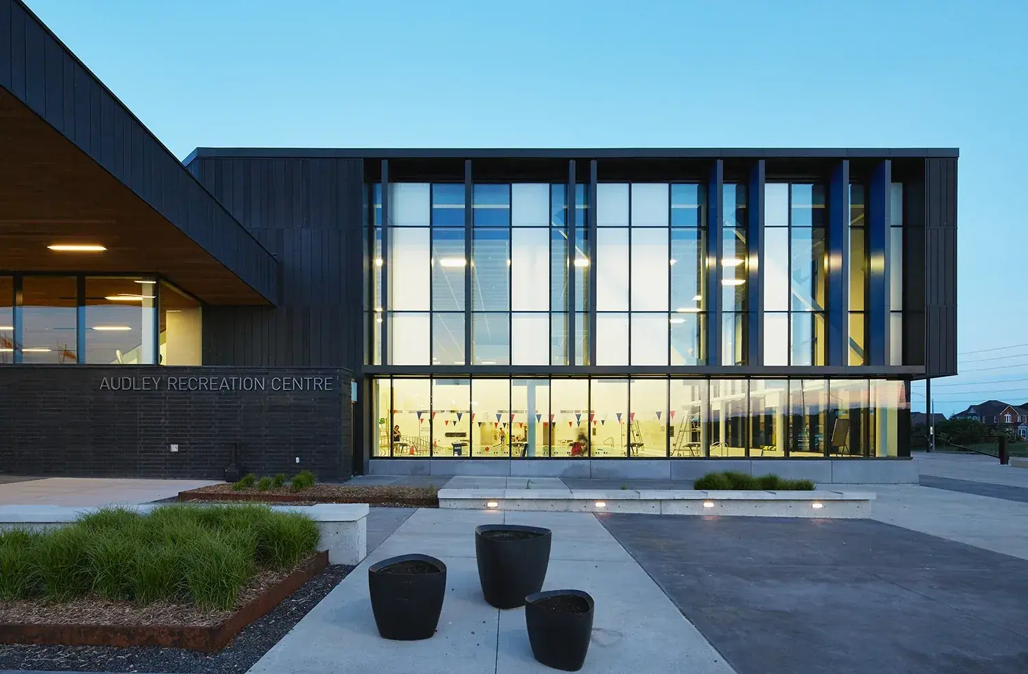Dusk exterior of the Audley Recreation Centre, Ajax, showing its glazed curtain wall